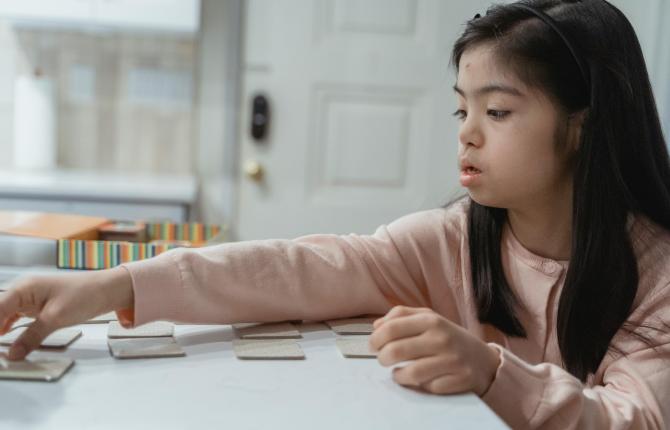 foto van een meisje met een beperking die een spelletje met kaartjes speelt